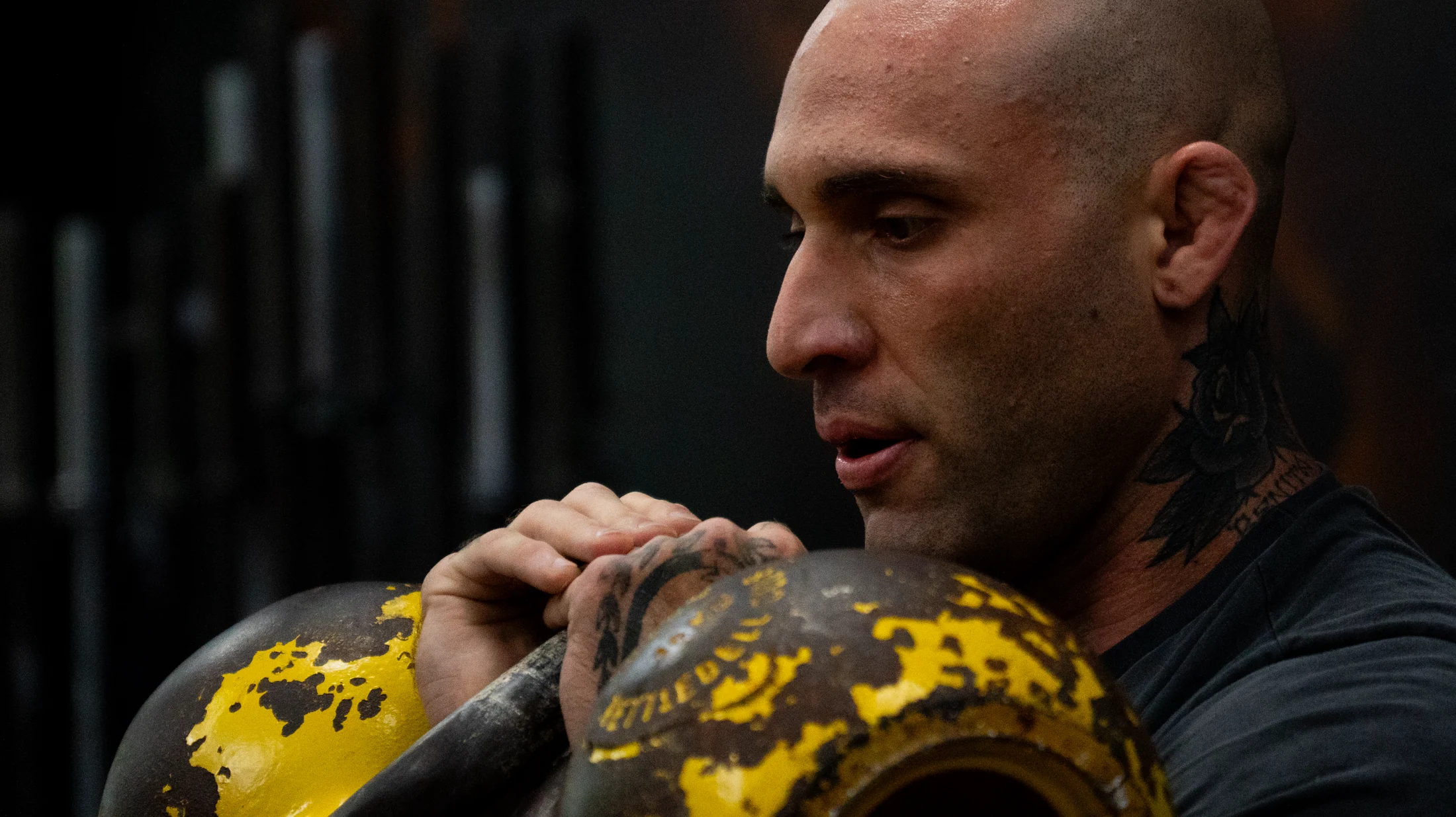 Atleta com dois kettlebells amarelos na posição de rack
